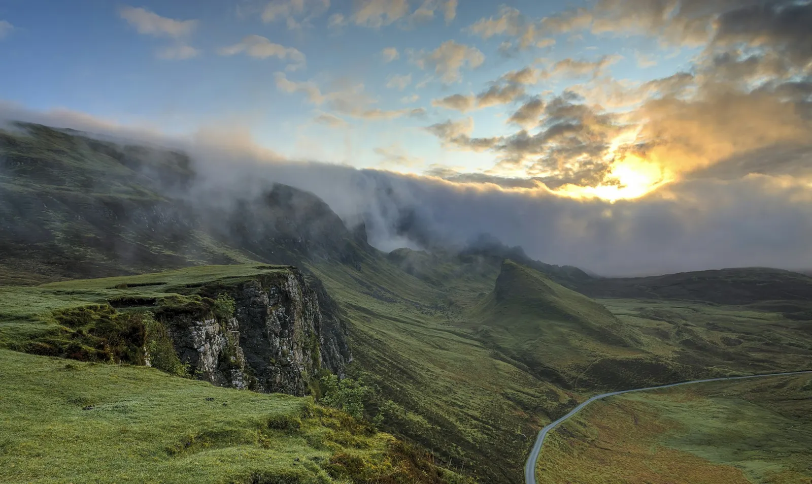 Mist lifting off green mountain peaks at sunrise